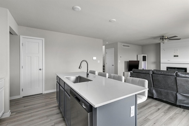 kitchen featuring light wood finished floors, dishwasher, visible vents, a sink, and ceiling fan