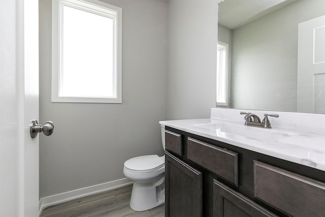 bathroom with wood finished floors, baseboards, vanity, and toilet