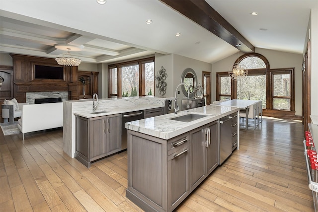 kitchen with stainless steel dishwasher, a sink, a center island with sink, an inviting chandelier, and gray cabinets