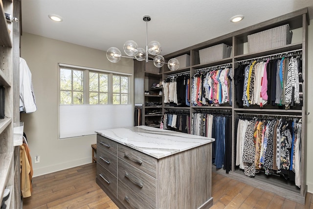 walk in closet featuring wood-type flooring and an inviting chandelier