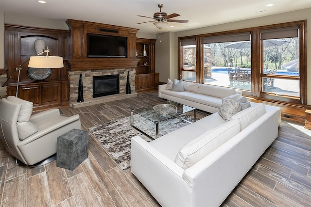 living area with a ceiling fan, wood finished floors, recessed lighting, and a fireplace