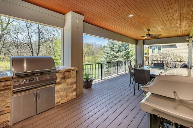 wooden deck with outdoor dining space, area for grilling, and a ceiling fan