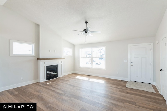 4412 NE 8th St, Ankeny, IA 50021 - unfurnished living room with a glass covered fireplace, wood finished floors, lofted ceiling, and a ceiling fan