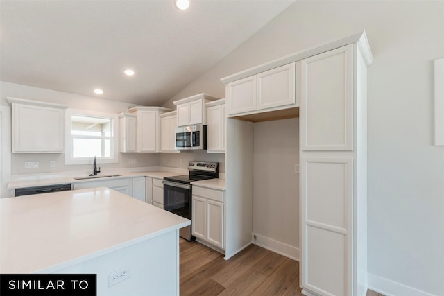 4412 NE 8th St, Ankeny, IA 50021 - kitchen featuring vaulted ceiling, light wood-style flooring, white cabinets, appliances with stainless steel finishes, and a sink