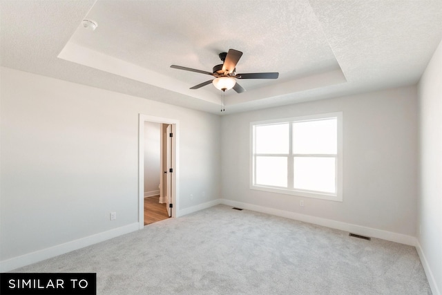 4412 NE 8th St, Ankeny, IA 50021 - empty room featuring a tray ceiling, light colored carpet, a ceiling fan, visible vents, and baseboards