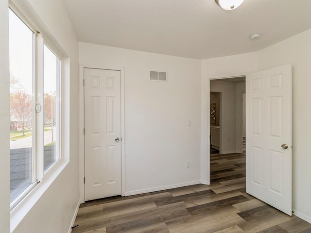 1710 Forest Ave, Des Moines, IA 50314 - unfurnished bedroom featuring baseboards, wood finished floors, multiple windows, and visible vents