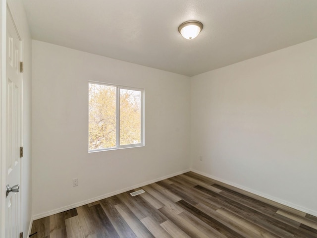1710 Forest Ave, Des Moines, IA 50314 - unfurnished room featuring baseboards, visible vents, and dark wood-style flooring