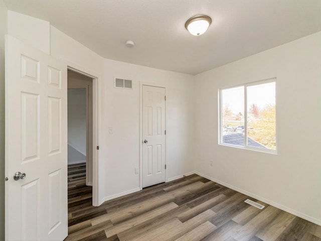 1710 Forest Ave, Des Moines, IA 50314 - unfurnished bedroom with baseboards, wood finished floors, and visible vents