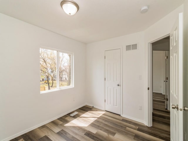 1710 Forest Ave, Des Moines, IA 50314 - unfurnished bedroom featuring baseboards, wood finished floors, and visible vents