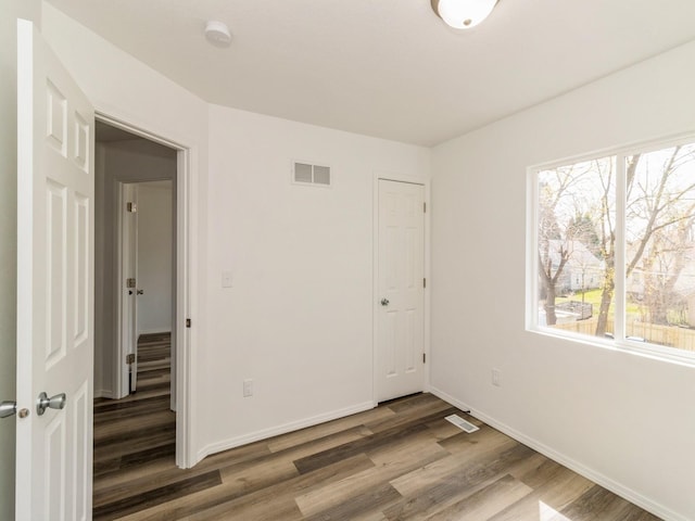 1710 Forest Ave, Des Moines, IA 50314 - unfurnished bedroom with baseboards, wood finished floors, and visible vents