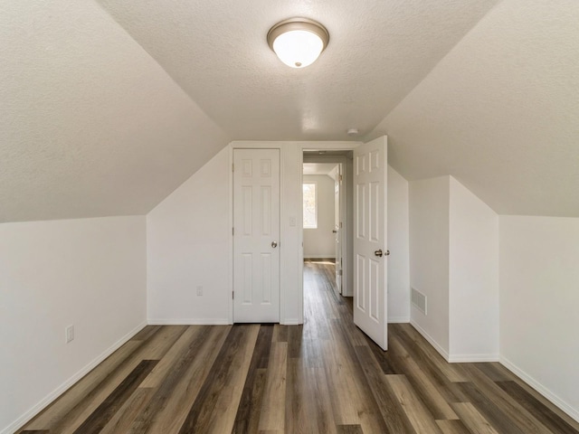1710 Forest Ave, Des Moines, IA 50314 - additional living space with lofted ceiling, visible vents, baseboards, a textured ceiling, and dark wood-style flooring