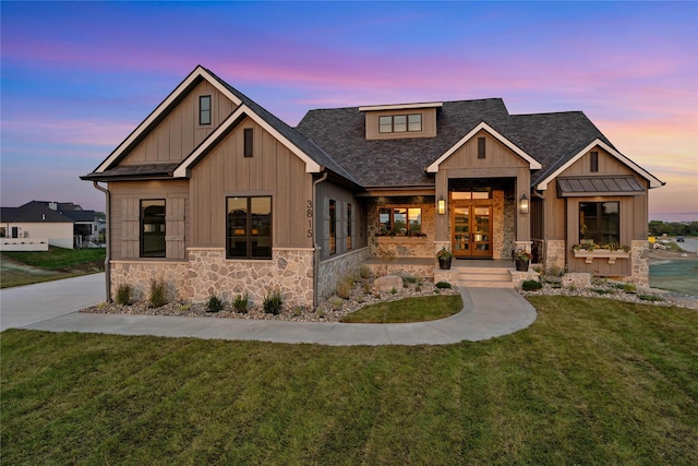 3815 NW 183rd St, Clive, IA 50325 - view of front of home with stone siding, french doors, board and batten siding, a yard, and roof with shingles