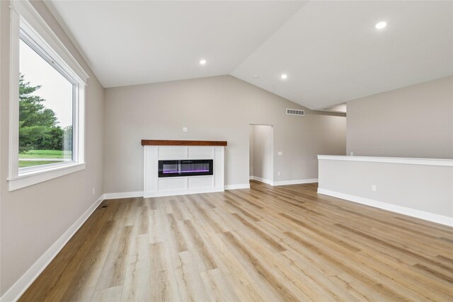 2311 N 8th Ave E, Newton, IA 50208 - unfurnished living room with light wood-style flooring, a glass covered fireplace, lofted ceiling, and recessed lighting