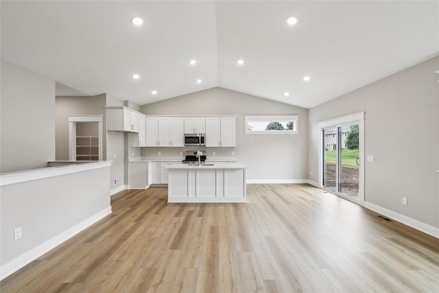 2311 N 8th Ave E, Newton, IA 50208 - kitchen with stainless steel microwave, white cabinets, light wood finished floors, light countertops, and a center island with sink