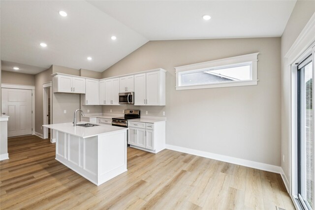 2311 N 8th Ave E, Newton, IA 50208 - kitchen with stainless steel appliances, white cabinets, light countertops, light wood-style flooring, and vaulted ceiling