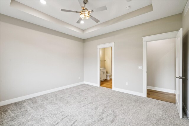 2311 N 8th Ave E, Newton, IA 50208 - unfurnished bedroom with carpet floors, a raised ceiling, recessed lighting, connected bathroom, and ceiling fan