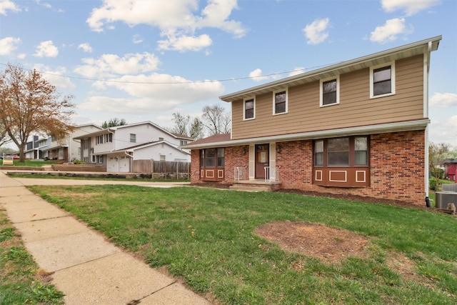 colonial inspired home with brick siding, a front lawn, and fence