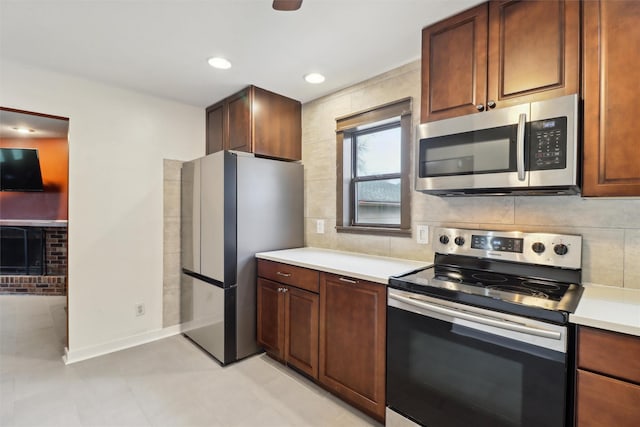 kitchen featuring light countertops, tasteful backsplash, a fireplace, and appliances with stainless steel finishes