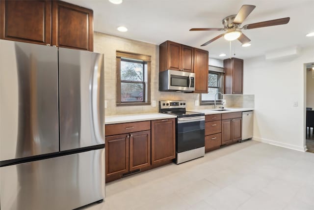 kitchen featuring light countertops, decorative backsplash, stainless steel appliances, and a sink