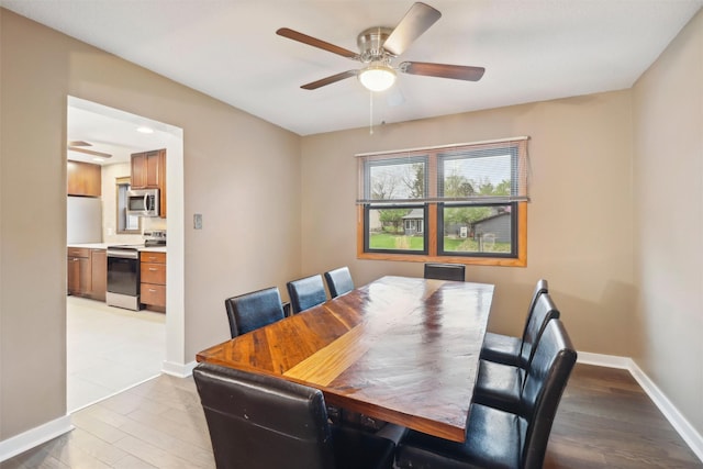 dining area featuring baseboards, a ceiling fan, and light wood-style flooring