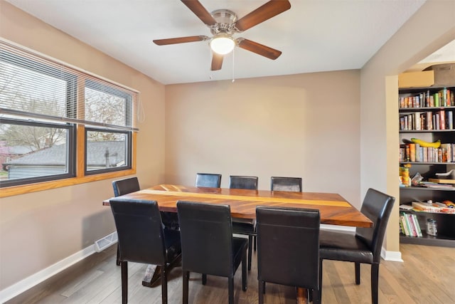 dining space featuring visible vents, hardwood / wood-style flooring, baseboards, and ceiling fan