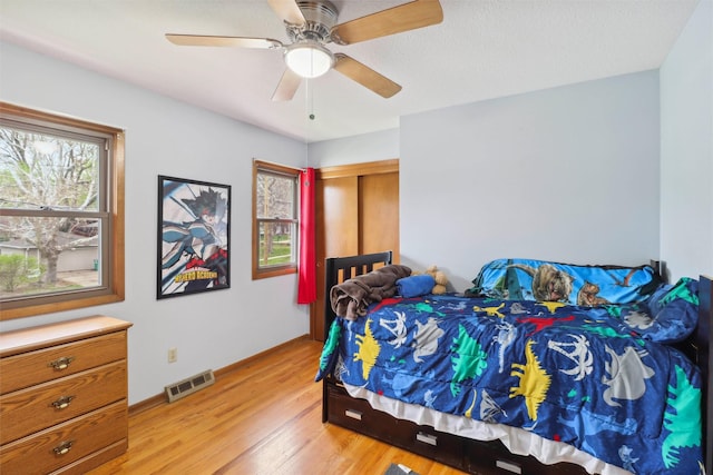 bedroom with light wood finished floors, visible vents, ceiling fan, and multiple windows