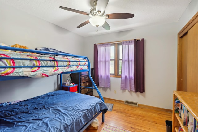 bedroom featuring light wood finished floors, baseboards, visible vents, and ceiling fan