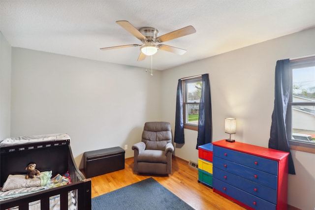 bedroom featuring baseboards, a ceiling fan, wood finished floors, and visible vents