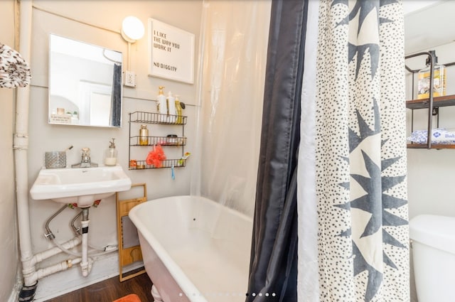 842 16th St Unit 4, Des Moines, IA 50314 - bathroom featuring wood finished floors, a sink, a freestanding bath, toilet, and a shower with shower curtain