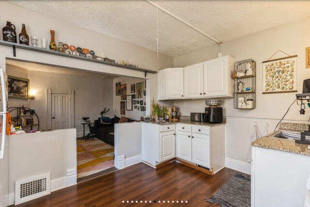 842 16th St Unit 4, Des Moines, IA 50314 - kitchen with dark wood-style floors, visible vents, light stone countertops, a textured ceiling, and white cabinetry