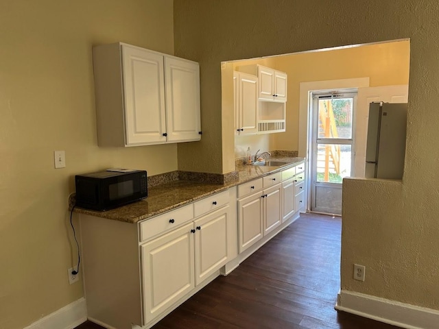 842 16th St Unit 4, Des Moines, IA 50314 - kitchen with dark wood-style floors, a sink, freestanding refrigerator, white cabinetry, and black microwave