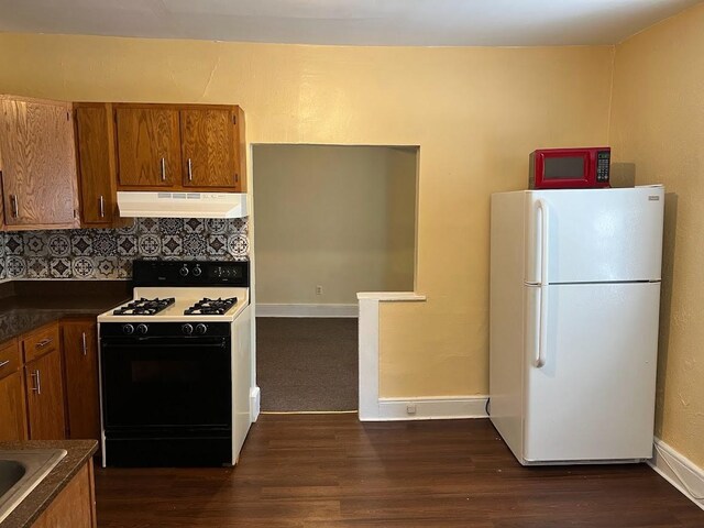 842 16th St Unit 4, Des Moines, IA 50314 - kitchen with dark countertops, gas range oven, under cabinet range hood, dark wood-type flooring, and freestanding refrigerator