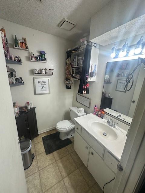bathroom with a textured ceiling, vanity, toilet, and visible vents