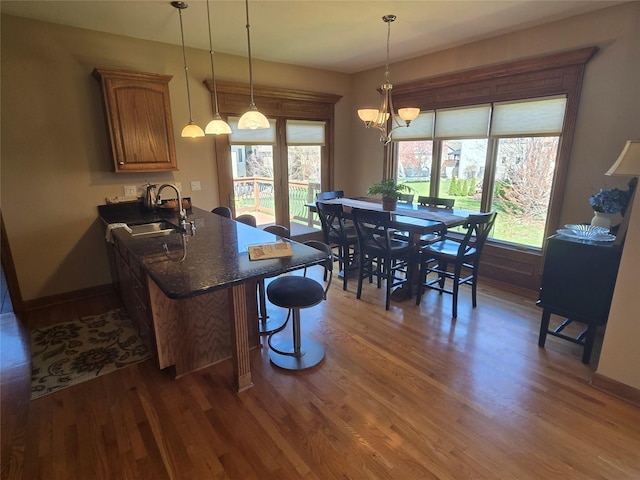 dining area featuring wood finished floors, baseboards, and an inviting chandelier