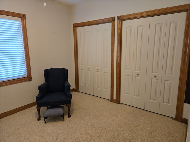 living area featuring light carpet and baseboards