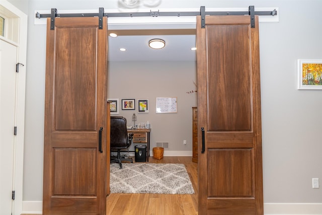 home office featuring a barn door, light wood-style flooring, baseboards, visible vents, and recessed lighting