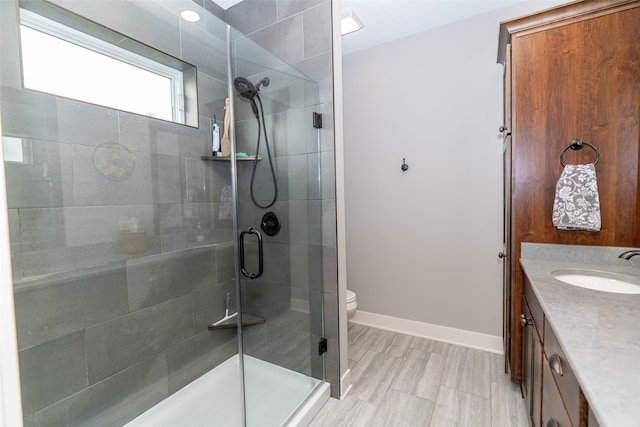 bathroom with vanity, baseboards, a shower stall, and toilet
