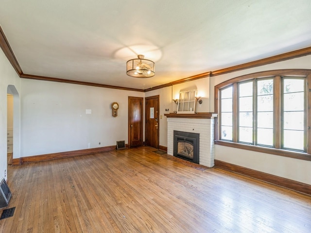 3826 Grand Ave, Des Moines, IA 50312 - unfurnished living room with hardwood / wood-style floors, a fireplace, crown molding, and arched walkways