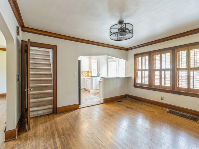3826 Grand Ave, Des Moines, IA 50312 - unfurnished living room with arched walkways, ornamental molding, and light wood-type flooring