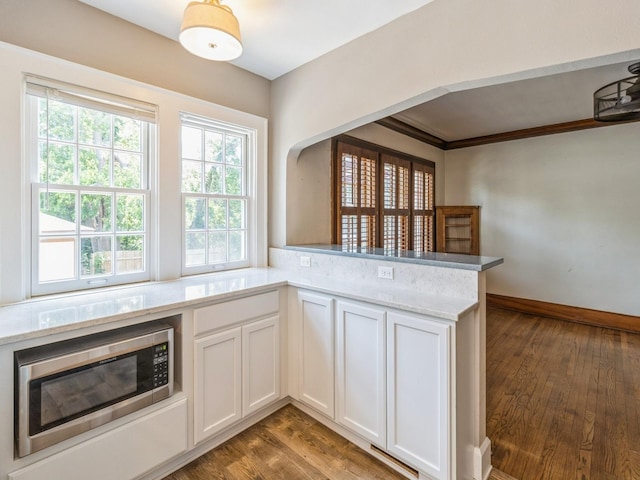 3826 Grand Ave, Des Moines, IA 50312 - kitchen featuring stainless steel microwave, light wood-style flooring, white cabinetry, light stone counters, and crown molding