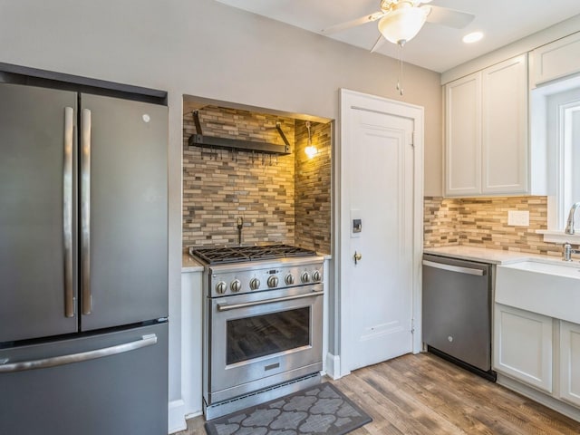 3826 Grand Ave, Des Moines, IA 50312 - kitchen featuring stainless steel appliances, tasteful backsplash, ceiling fan, wall chimney range hood, and white cabinetry