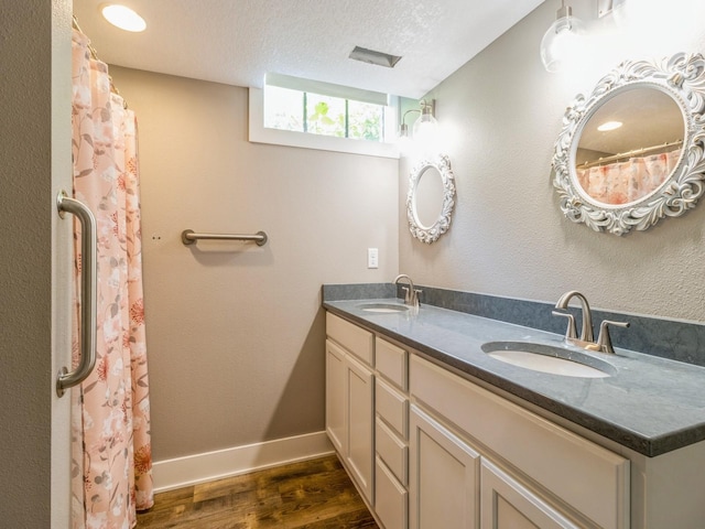 3826 Grand Ave, Des Moines, IA 50312 - full bathroom featuring wood finished floors, double vanity, and a textured ceiling