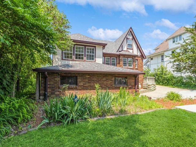 3826 Grand Ave, Des Moines, IA 50312 - tudor home featuring a front yard, brick siding, and a shingled roof