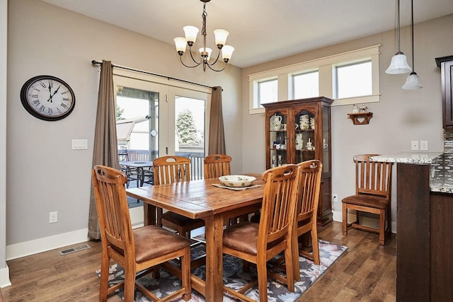 dining room with dark wood finished floors, visible vents, baseboards, and an inviting chandelier
