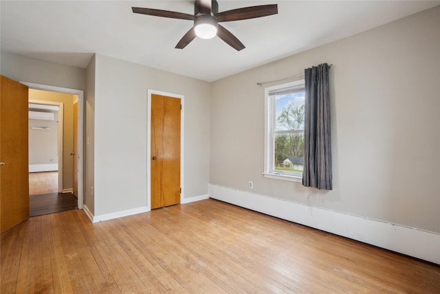 1804 E 33rd St, Des Moines, IA 50317 - unfurnished bedroom featuring wood-type flooring, baseboards, ceiling fan, a wall mounted air conditioner, and a baseboard radiator