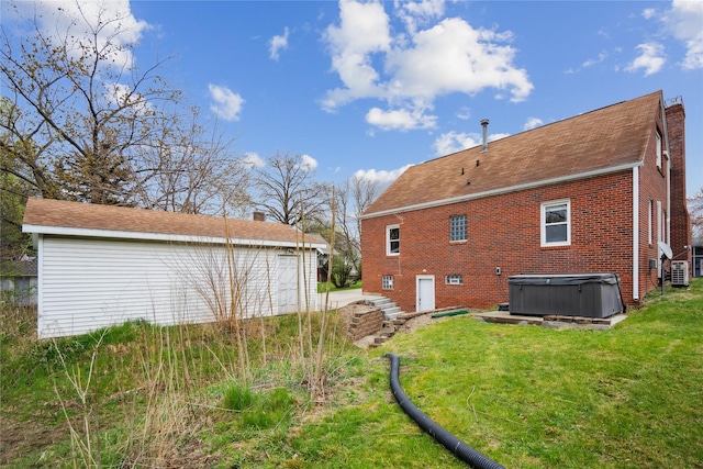 1804 E 33rd St, Des Moines, IA 50317 - rear view of house with a hot tub, a lawn, and brick siding