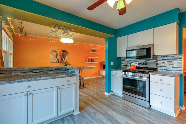 310 E Emma Ave, Des Moines, IA 50315 - kitchen with stainless steel appliances, backsplash, white cabinetry, light wood-style flooring, and a ceiling fan