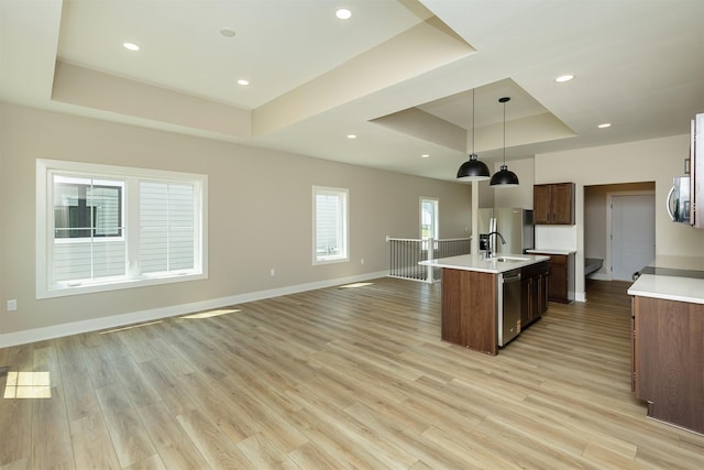 1204 Westview Dr, Huxley, IA 50124 - kitchen featuring a tray ceiling, appliances with stainless steel finishes, light countertops, a center island with sink, and light wood-style floors