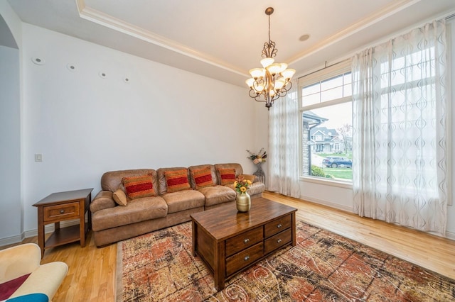 9289 Winterberry Ct, West Des Moines, IA 50266 - living room featuring wood finished floors, ornamental molding, a raised ceiling, baseboards, and a notable chandelier