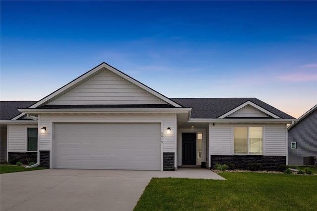 ranch-style home featuring a yard, central AC, driveway, stone siding, and a garage